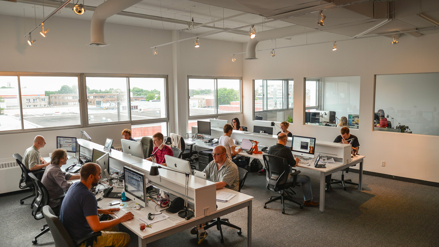 Employés de Casserole travaillant sur des ordinateurs dans un bureau moderne et lumineux.